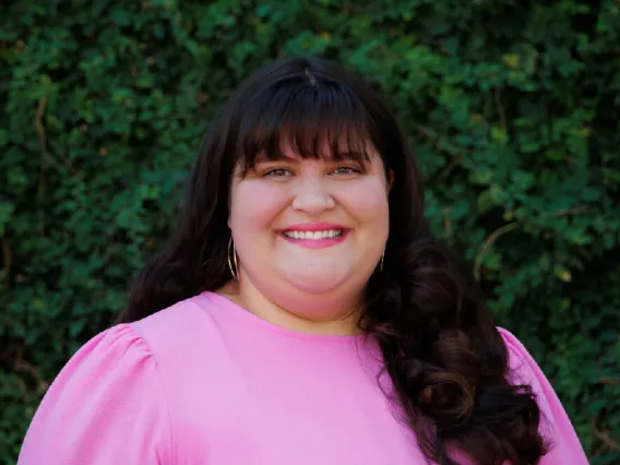 Photo of woman with a pink blouse and dark, long hair.