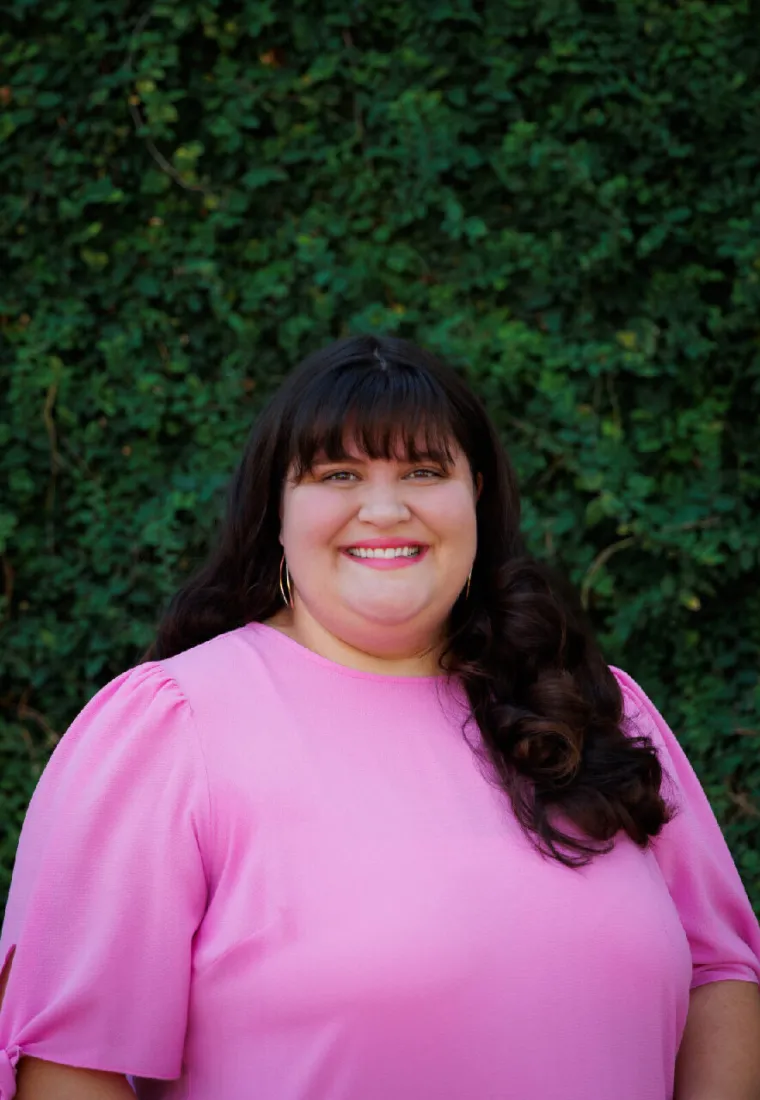 Photo of woman with a pink blouse and dark, long hair.